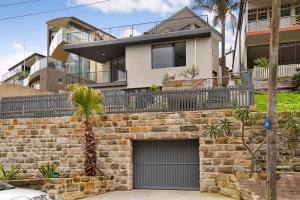 a brick wall with a garage in front of a house at BRON455B - Bronte Beach House with Ocean Views in Sydney