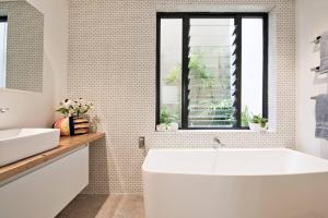 a bathroom with a white tub and a window at BRON455B - Bronte Beach House with Ocean Views in Sydney