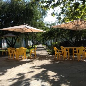 un grupo de mesas amarillas y sillas bajo sombrillas en Tur Service Guest House, en Vardané