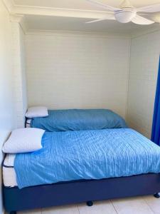
a bed in a bedroom with a blue blanket at Orchid Beach Apartments in Fraser Island
