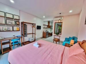 um quarto com uma cama rosa, uma secretária e cadeiras em Mai Home - Apartment & Homestay em Ho Chi Minh