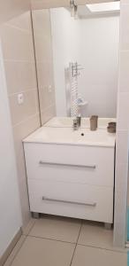 a white bathroom with a sink and a mirror at villa des lauriers roses in Valras-Plage