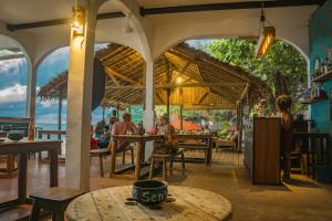 MadirokelyにあるChez Sengaのビーチ沿いのレストランで、テーブル席に座る人々と一緒に食事をする