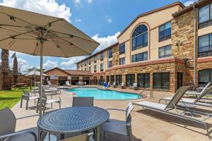 un patio con mesa, sillas y piscina en Holiday Inn Express & Suites Austin NW – Lakeway, an IHG Hotel, en Lakeway