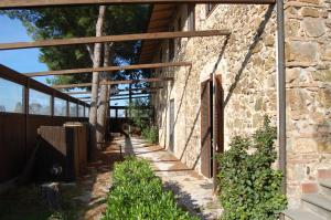 a stone wall with a pathway next to a building at Podere Valmarina in Follonica