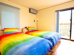 two beds in a room with rainbow colored sheets at 天弓イン Tenkyu Inn in Kachabaru