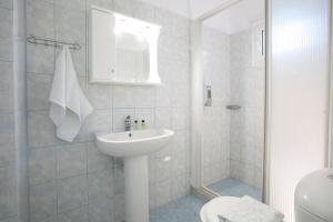a white bathroom with a sink and a shower at Spacious Studios Lefkada Mountain View Near Beach in Dhráganon
