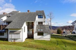 a white house with a gray roof on a green yard at Sunrise Timberline I7 in Killington