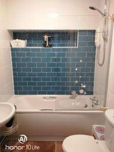 baño con bañera y pared de azulejos azules en Rhodri Apartment with Sea Views and Sun Terrace en Trearddur