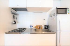 a white kitchen with a sink and a refrigerator at Salon Shibuya - Vacation STAY 78188 in Tokyo