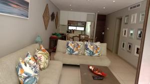 een woonkamer met een bank en een tafel bij Zimbali Suites 223 in Ballito