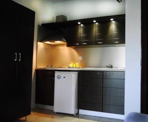 a kitchen with black cabinets and a white refrigerator at Blue Bay Beach Hotel in Koinyra