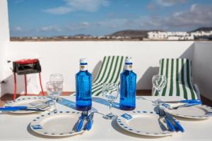 Una mesa con botellas y vasos azules encima. en Home2Book Charming House El Cotillo, en Cotillo