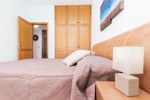 1 dormitorio con 1 cama y 1 mesa con lámpara en Home2Book Charming House El Cotillo, en Cotillo