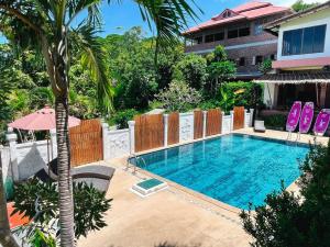 a swimming pool with a palm tree and a building at Bounty Resort in Haad Son