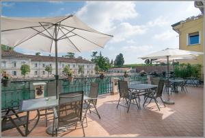 un patio con mesas, sillas y una sombrilla en Fiori sull'Acqua Apartments, en Peschiera del Garda