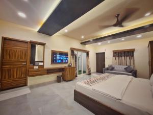 a bedroom with a bed and a tv and a couch at RK RESORTS in kāraikāl