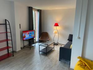 ein Wohnzimmer mit einem TV und einem Sofa in der Unterkunft Au Saint-Hubert, Appartement 3 chambres Valenton in Valenton