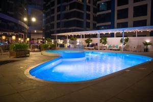 a large swimming pool in a city at night at Swiss-Belresidences Juffair in Manama