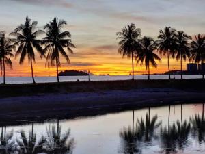 um grupo de palmeiras na praia ao pôr do sol em Port Dickson PD Malacca Straits Homestay em Porto Dickson