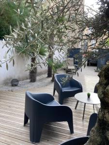 eine Terrasse mit Stühlen, einem Tisch und einem Baum in der Unterkunft Maison d'hotes L'atelier du Charmois in Vandoeuvre-lès-Nancy