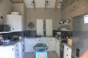 a kitchen with white cabinets and a brick wall at Pecan Tree Cottage in Montagu