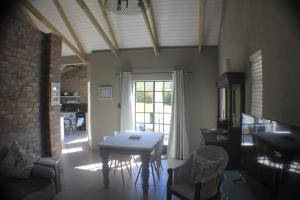 d'un salon avec une table, des chaises et une fenêtre. dans l'établissement Pecan Tree Cottage, à Montagu