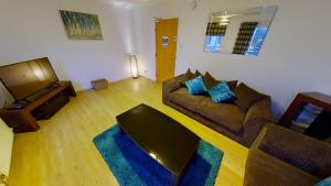 a living room with a couch and a television at Orange Town House - Shaw Road, Only 6 Minutes to City Centre in Aberdeen