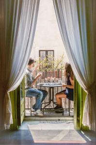un hombre y una mujer sentados en una mesa en un balcón en Casa D'aria, en Catania
