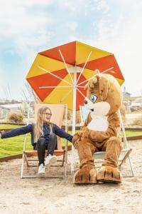 a woman sitting in a chair next to a giant teddy bear at Skrea Camping in Falkenberg