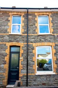 a brick building with three windows and a black door at Amazing new 3 double bed house in staple hill! in Bristol