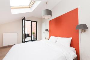 een slaapkamer met een wit bed en een oranje accentmuur bij Smartflats Design - Opera in Luik