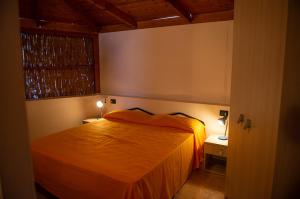 ein Schlafzimmer mit einem orangenen Bett und einem Fenster in der Unterkunft Lido Paradiso Resort in Pisciotta