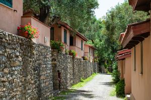 an alley with a stone wall and flowers on a building at Lido Paradiso Resort in Pisciotta