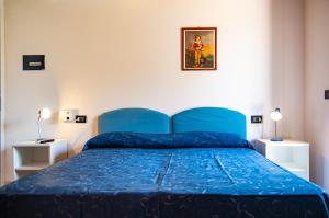 ein blaues Bett in einem Schlafzimmer mit zwei Lampen in der Unterkunft Lido Paradiso Resort in Pisciotta
