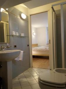 a bathroom with a sink and a toilet and a bed at Villa Paola in Lavarone