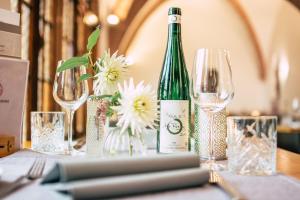 a bottle of wine sitting on a table with glasses at Boutiquehotel Kloster Pfalzel in Trier