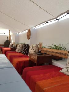 a room with four beds with red and orange sheets at Riad A La Belle Etoile in Sale