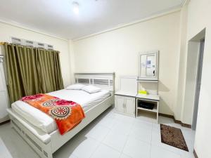 a white bedroom with a bed and a desk at Rumah Umi AWR in Bukittinggi