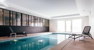 a swimming pool with two chairs in a building at Holiday Suites Nieuwpoort in Nieuwpoort