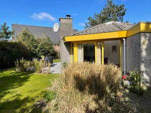 ein gelbes Haus mit einem Garten mit Gras in der Unterkunft Zeester 5 personen * in Julianadorp