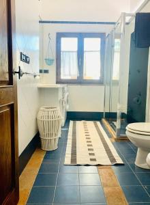 La salle de bains bleue et blanche est pourvue de toilettes et d'une fenêtre. dans l'établissement Villa San Regolino whit private pool, à Radicondoli