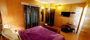 a bedroom with a bed with a purple blanket at Ikraam Inn Bed & Breakfast in Srinagar