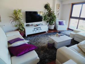 Elle comprend un salon doté d'un mobilier blanc et d'oreillers violets. dans l'établissement Duplex grandes cristaleras impresionantes vistas, à Ourense