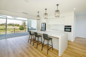 una cocina con encimera blanca y taburetes de bar en Fairway 43, en Yarrawonga