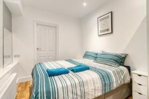 a bedroom with a bed with blue pillows on it at Holland Park Apartment in London