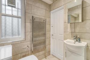 Un baño con lavabo, inodoro y ventana. en Holland Park Apartment, en Londres 13 fotos más