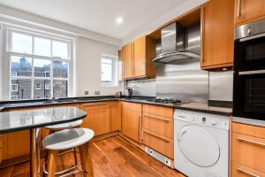 een keuken met houten kasten en een witte vaatwasser bij Marylebone Apartment in Londen