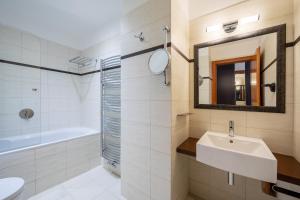 a bathroom with a sink and a tub and a mirror at Design Merrion Hotel in Prague
