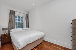 - une chambre blanche avec un lit et une fenêtre dans l'établissement Marylebone Apartment, à Londres
